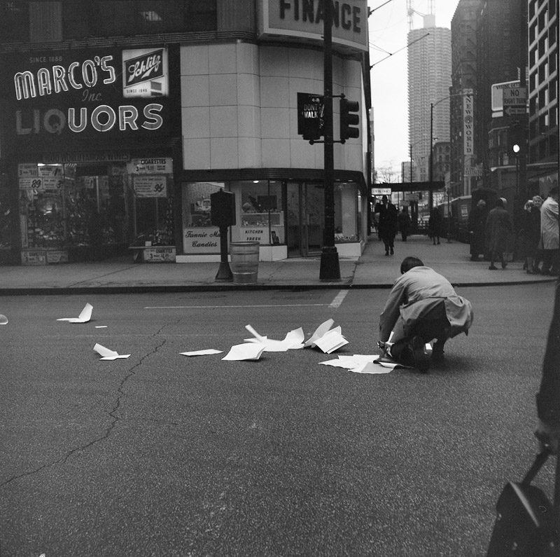 Vivian Maier, Chicago, Man on Street Collecting Scattered Papers. Circa 1965.