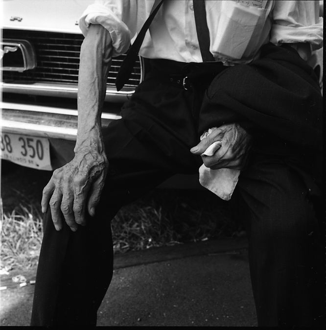 Vivian Maier, Wilmette, IL. Man Sitting on Car Bumper. July 1968.