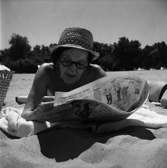 Vivian Maier, Wilmette, IL. Woman reading paper on Beach. Circa 1960.